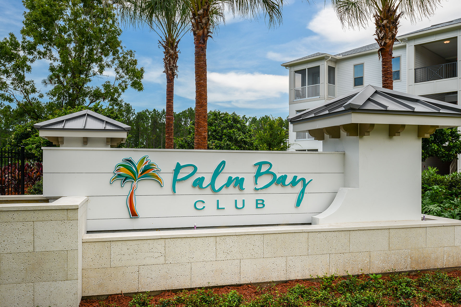 Front sign of Palm Bay Club complex with palm trees