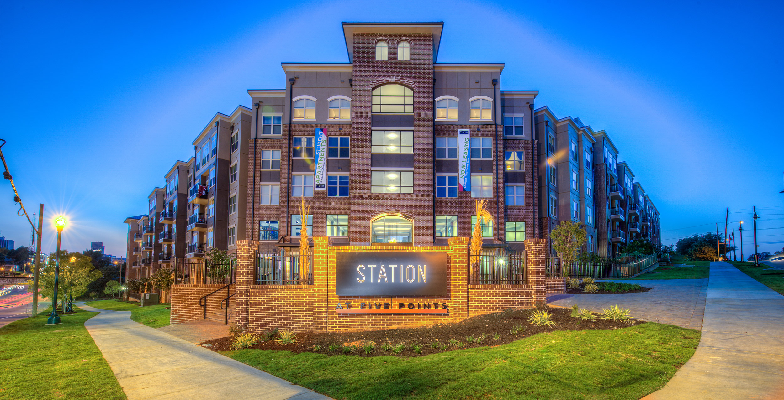 Multi level student housing at night with Station at Five Points sign