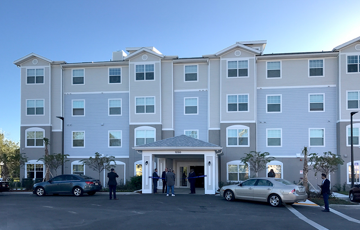 Multi level senior living facility front entrance with people at door