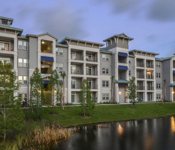 Multi story apartments with porches by small pond