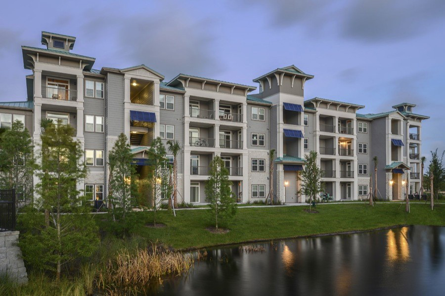 Multi story apartments with porches by small pond