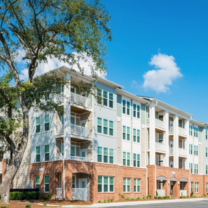 Teal and brown multi story apartment complex angle view with tree