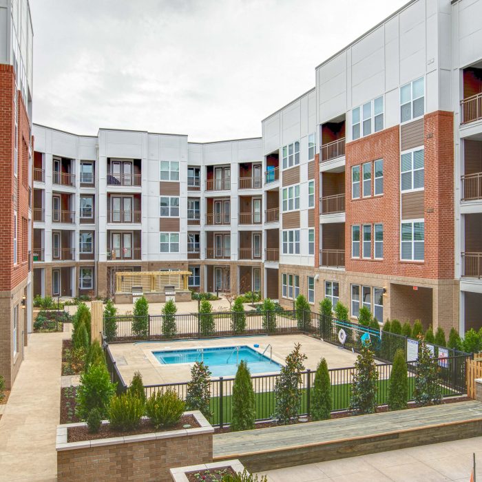 Multi story apartment complex pool area surrounded by plants