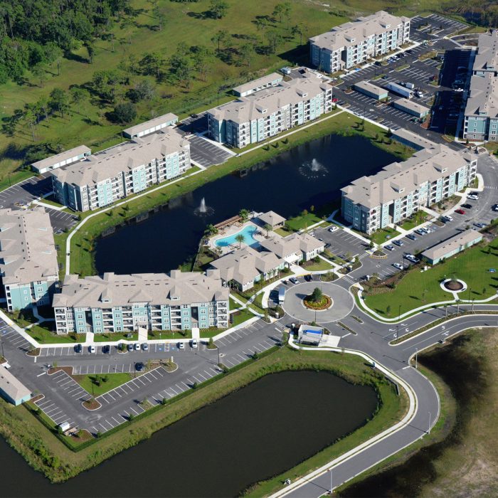 Multi story apartment complex with pond and fountains aerial shot