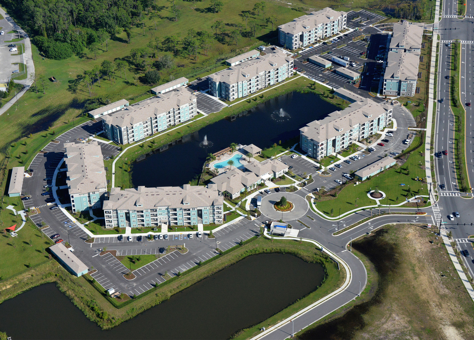 Multi story apartment complex with pond and fountains aerial shot