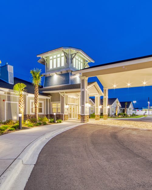 Senior living facility with palm trees entrance at evening