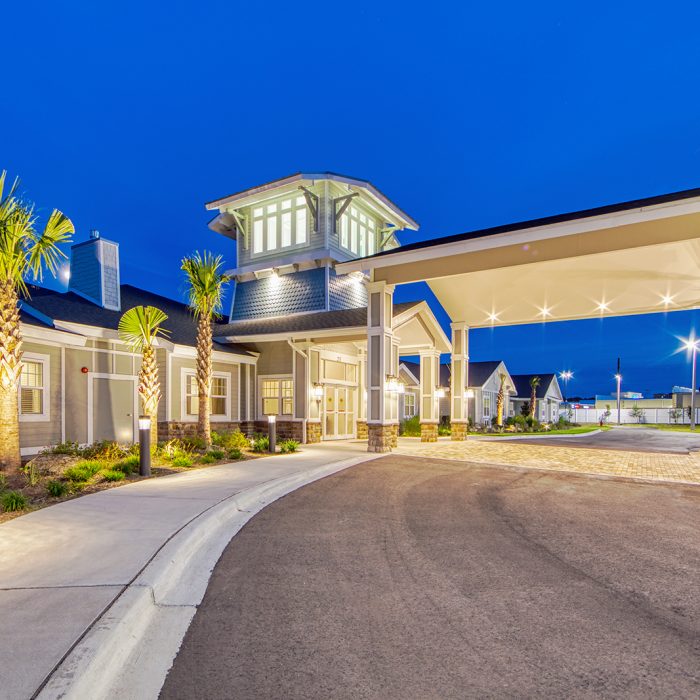Senior living facility with palm trees entrance at evening