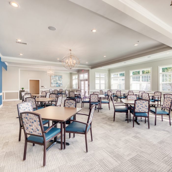 Lounge area with four person tables and chairs and windows