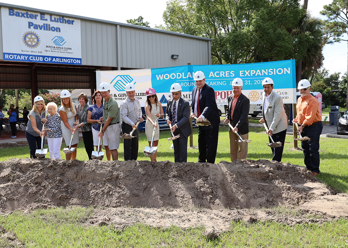 Summit employees in professional attire digging dirt at new construction site