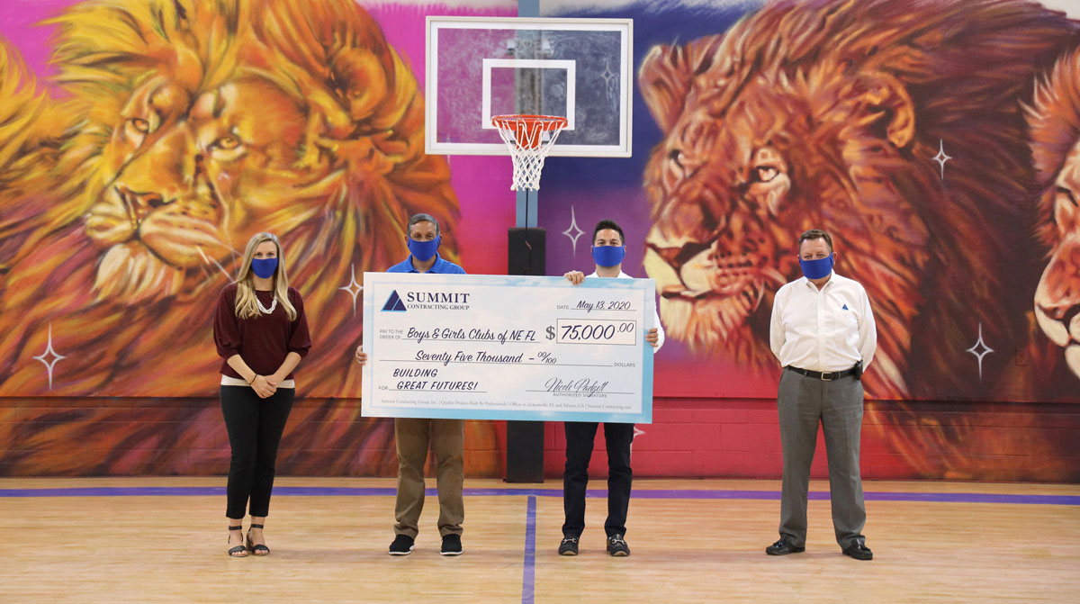 people standing in a gym holding a large check