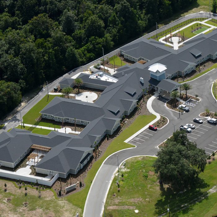 Aerial view of senior living facility with multiple living quarters and palm trees