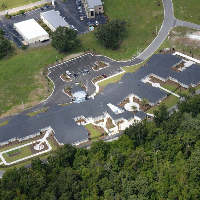 Aerial view of senior living facility with multiple living quarters and palm trees