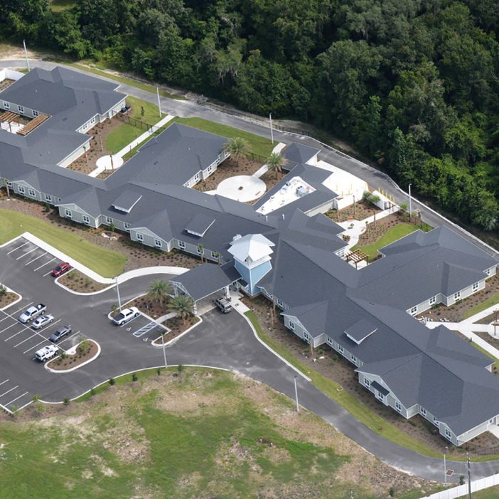 Aerial view of senior living facility with multiple living quarters and palm trees