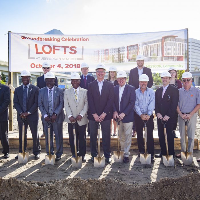 Executives and contractors smiling with shovels at new development ground