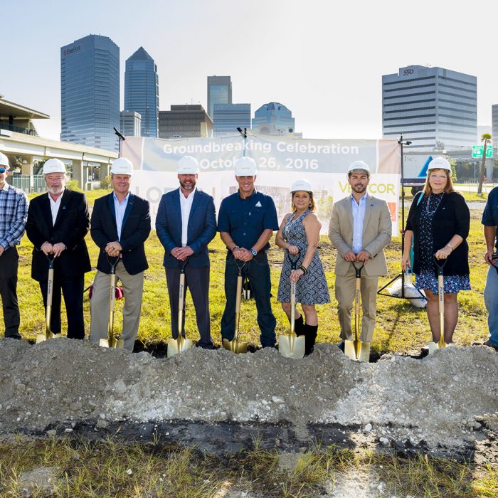 Executives and contractors smiling with shovels at new site