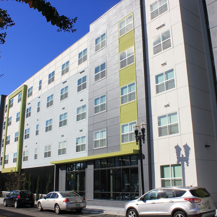 Multi story apartment complex with cars parked beside it