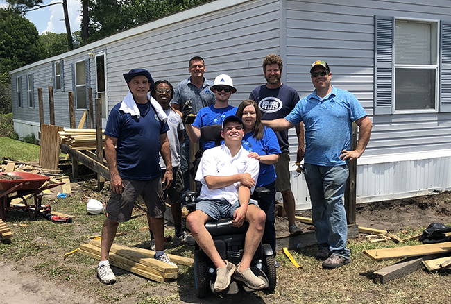 Summit employees working on site with man in wheelchair in front of trailer home