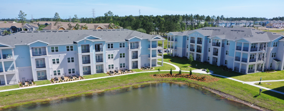 view of 3 story apartment buildings and blue sky