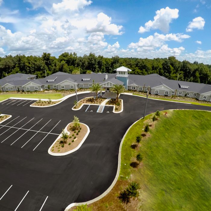 Aerial view of senior living facility with multiple living quarters and palm trees