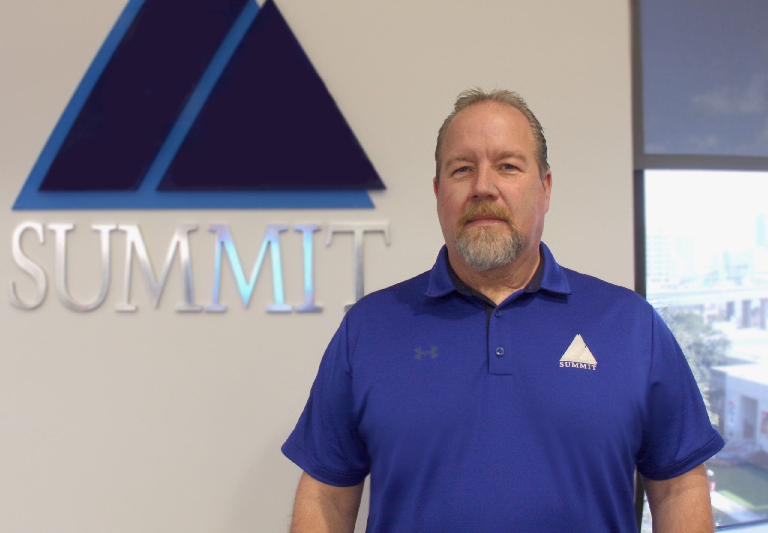 Portrait of Tom Born in front of Summit Logo