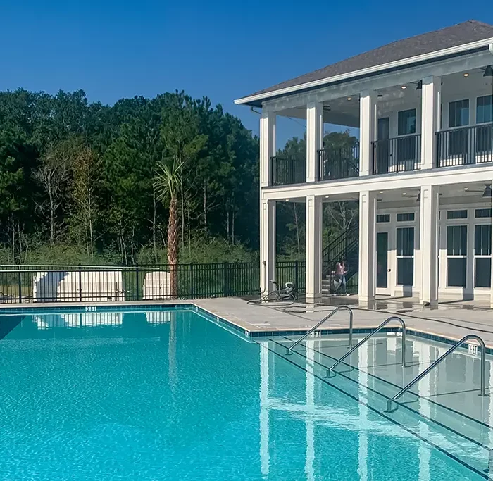 swimming pool with 2-story building and trees