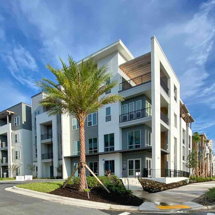 entrance to 4 story apartment building with palm tree