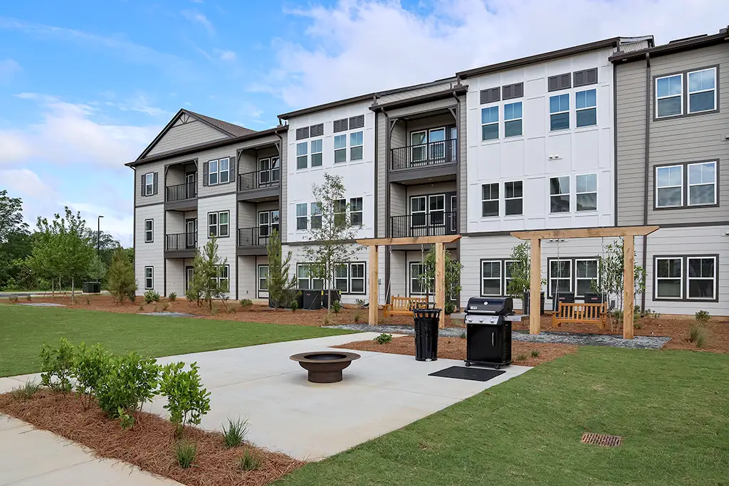 3 story apartment building with outdoor grilling patio and swing chairs