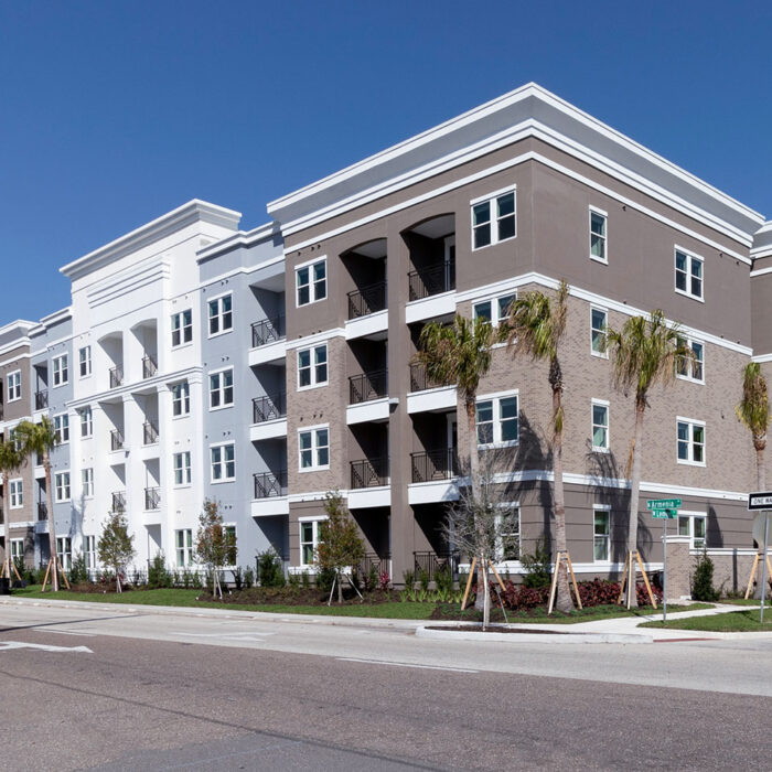 4 story apartment building with white and natural stone colored facade