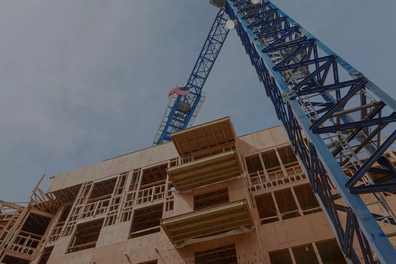 background image of wood framing of an apartment building and a blue crane