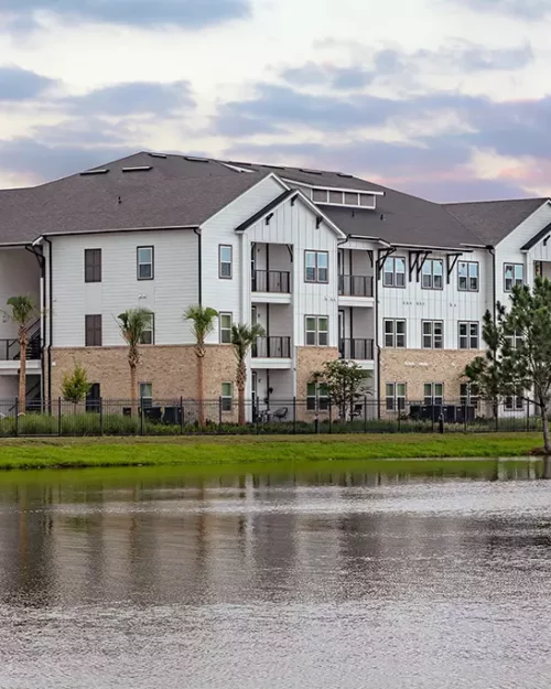 3 story apartment building with stone facade next to a lake