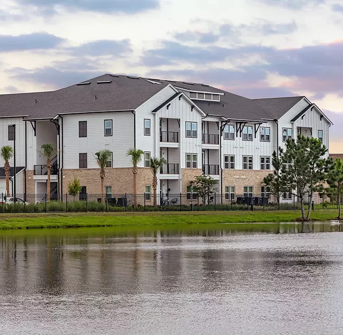 3 story apartment building with stone facade next to a lake