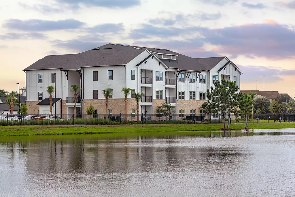 3 story apartment building with stone facade next to a lake