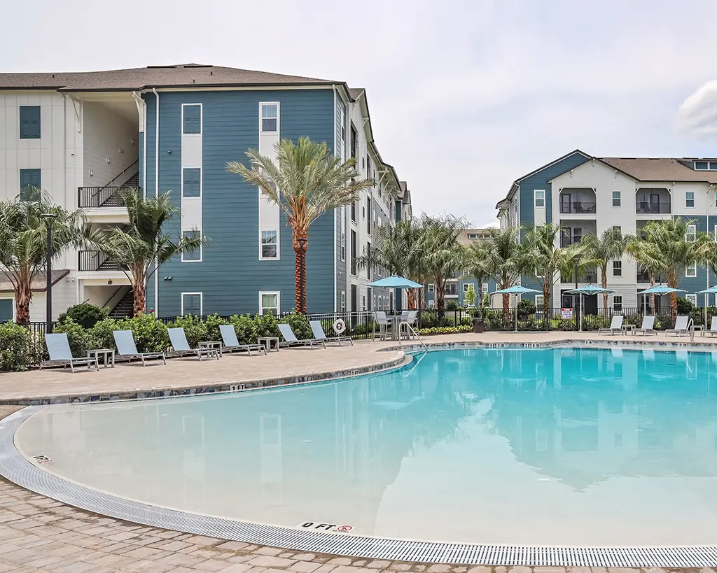 4 story apartment building with pool in the foreground and palm trees