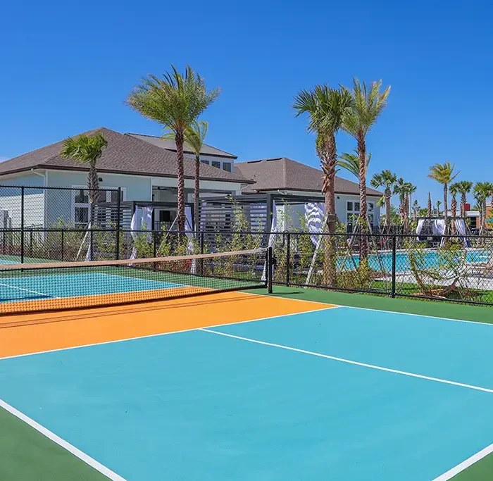 pickleball courts with palm trees and a clubhouse building in the background