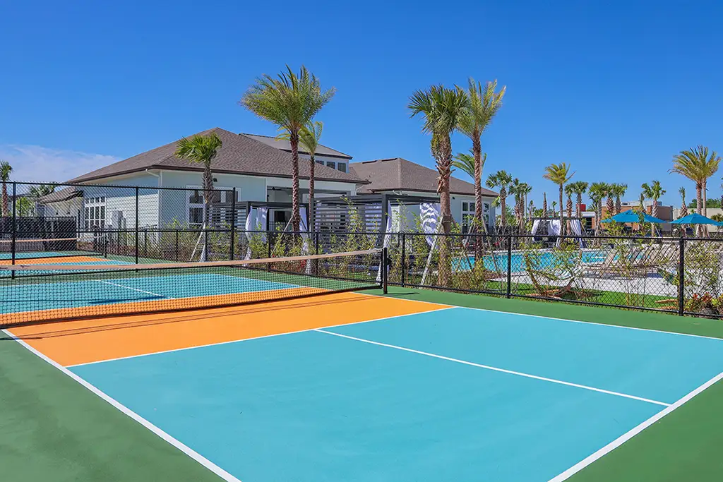 pickleball courts with palm trees and a clubhouse building in the background