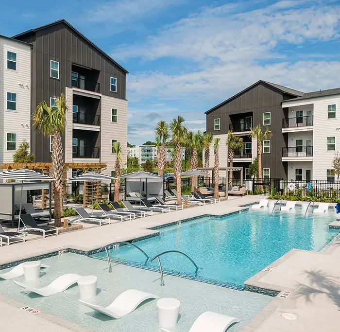 swimming pool surrounded by lounge chairs and 2 apartment buildings