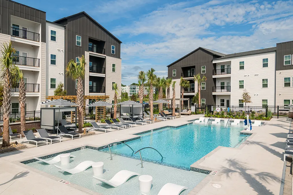 swimming pool surrounded by lounge chairs and 2 apartment buildings