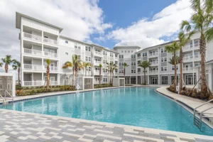 4 story apartment building with swimming pool and palm trees