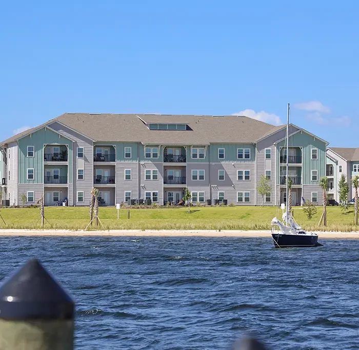 view of apartment building from the water with a sailboat moored