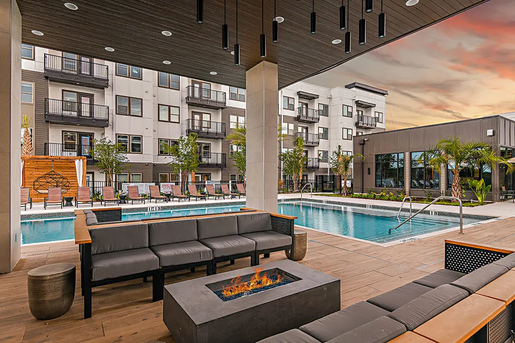 outdoor lounge with fire pit next to swimming pool and 4-story apartment building