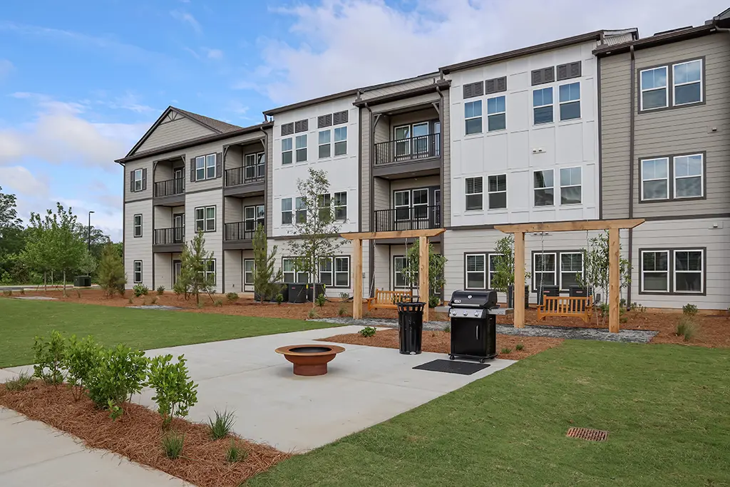 3 story apartment building with outdoor grilling patio and swing chairs