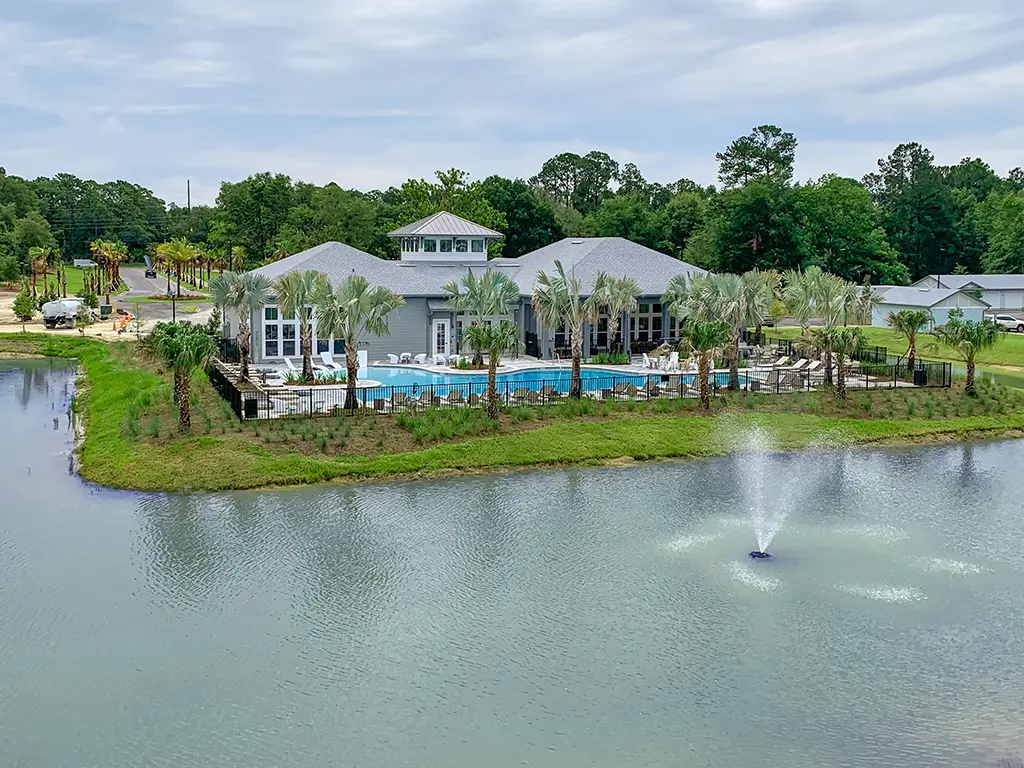 clubhouse with a pool and palm trees next to a lake