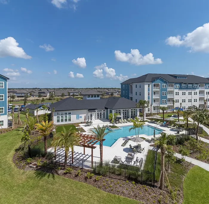 aerial view looking down at apartment buildings with a swimming pool and palm trees with a sidewalk paths