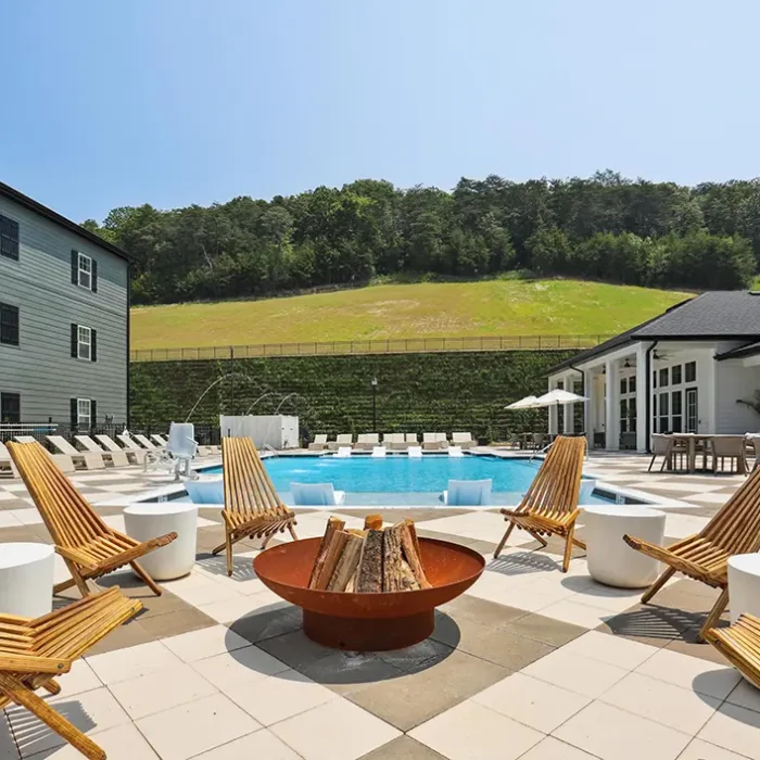 firepit surrounded by chairs next to a pool