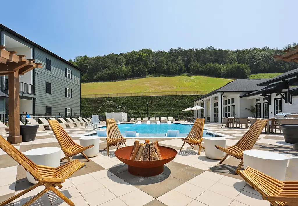 firepit surrounded by chairs next to a pool