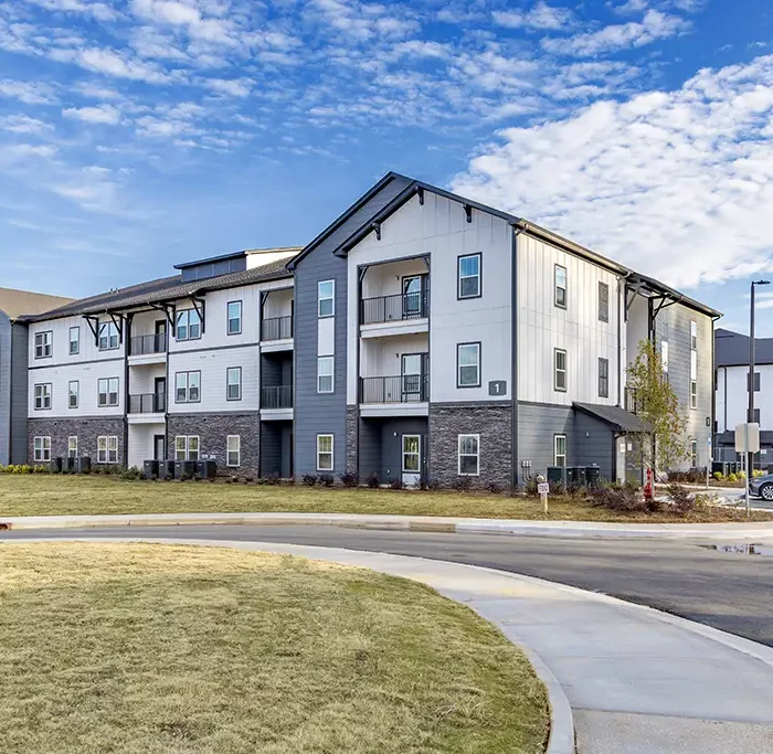 3 story apartment building with driveway and sidewalk in foreground