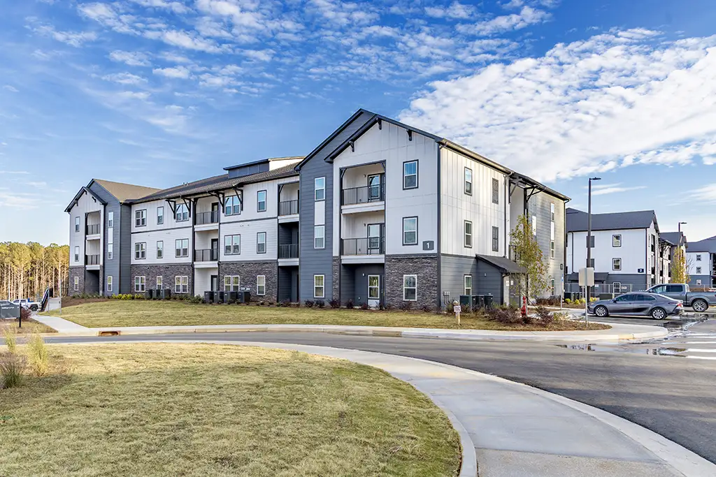 3 story apartment building with driveway and sidewalk in foreground