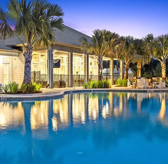 swimming pool and clubhouse building at night with palm trees