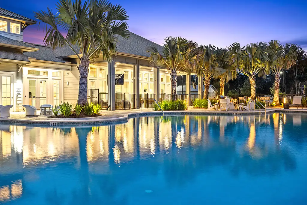 swimming pool and clubhouse building at night with palm trees