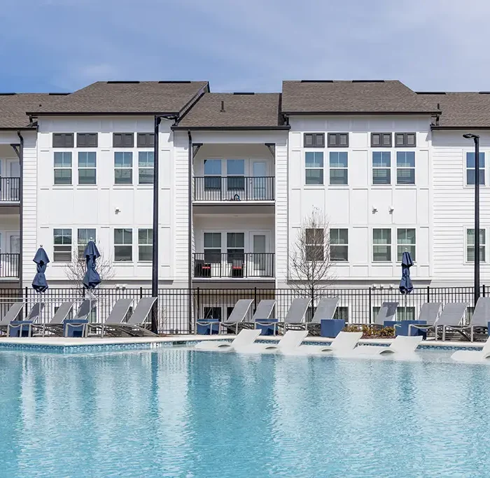 3 story apartment building with balconies and swimming pool in the foreground